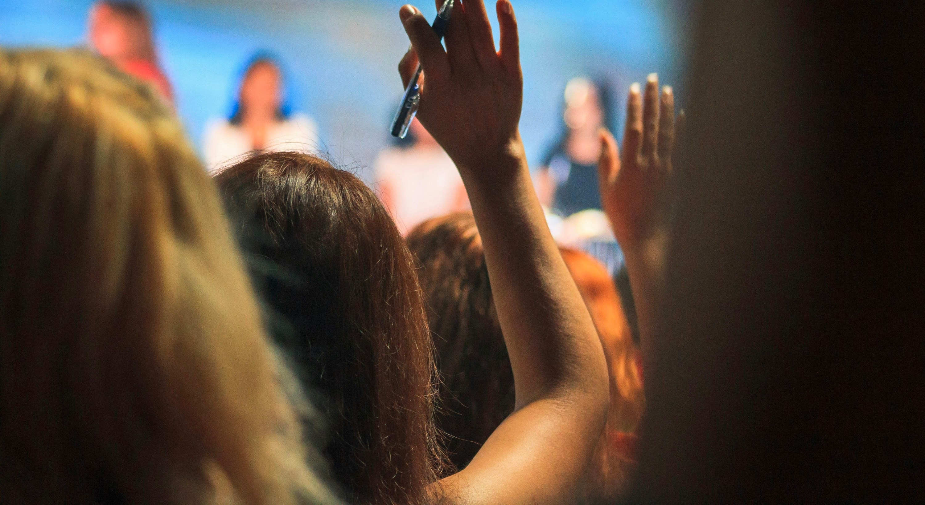 Una mano alzata fra il pubblico per fare una domanda durante un incontro