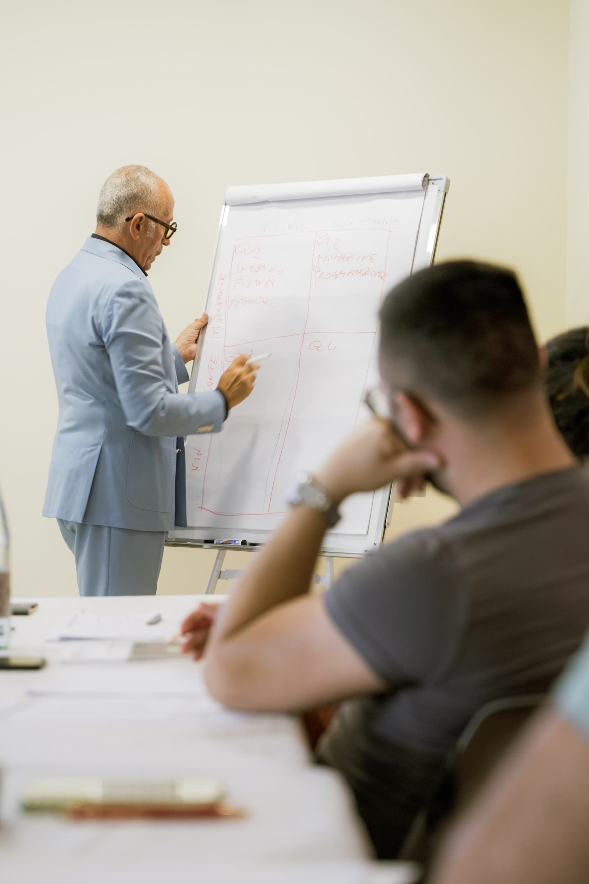 Maurizio Culicchia spiega alla lavagna a fogli mentre un imprenditore segue in primo piano